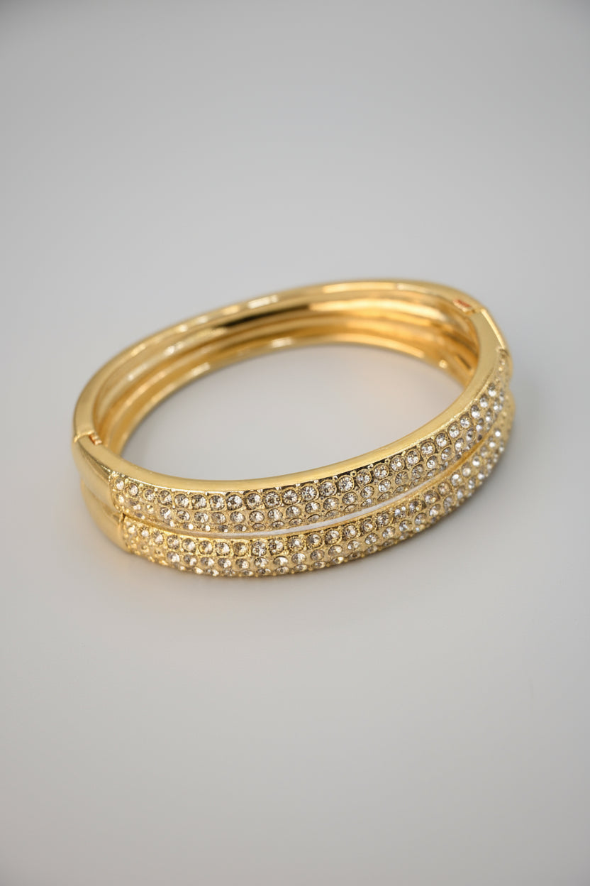 Gold bracelet with crystal embellishments on a beige background