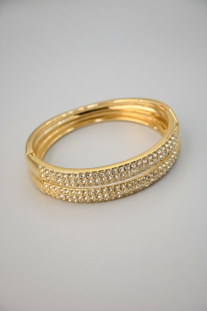 Gold bracelet with crystal embellishments on a beige background