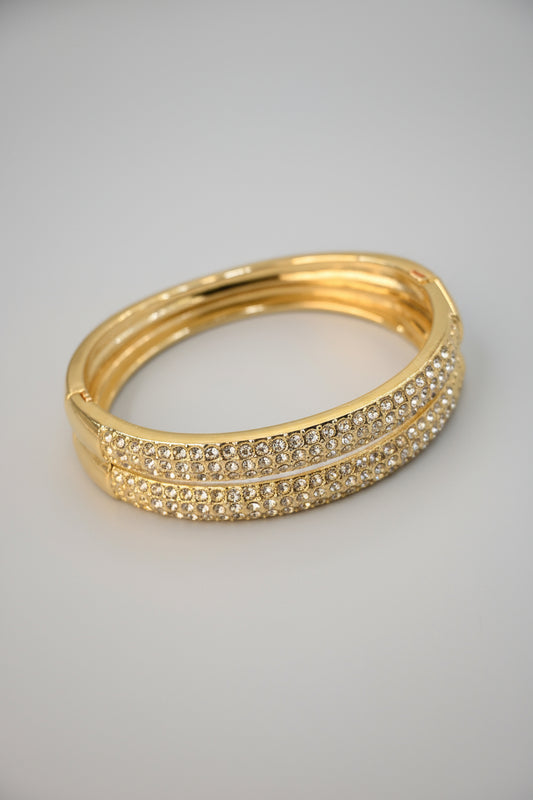 Gold bracelet with crystal embellishments on a beige background