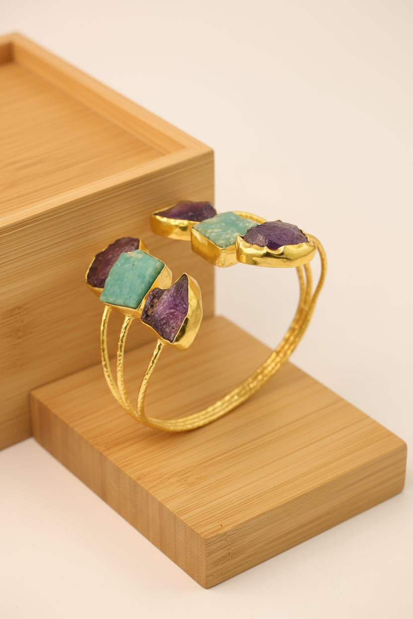 Gold bracelet with colorful gemstones on a wooden surface